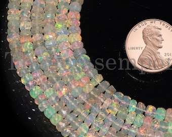 May include: A strand of iridescent white opal beads, approximately 4mm in size, with a US penny for scale. The beads are faceted and have a slight shimmer.