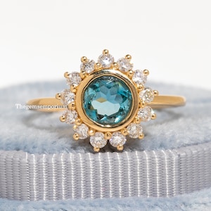 May include: A gold ring with a blue gemstone surrounded by a halo of smaller diamonds.
