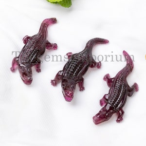 May include: Three purple gemstone alligator carvings. The alligators are detailed and have a textured surface.
