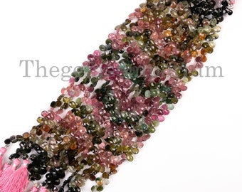 May include: A strand of faceted gemstone beads in shades of pink, green, and black. The beads are strung on a cord with pink tassels at each end.