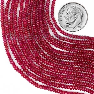 Puede incluir: Una hebra de cuentas de color rojo rubí, de aproximadamente 4 mm de diámetro, con un acabado liso y pulido. Las cuentas están enhebradas en un hilo transparente y están dispuestas en un patrón suelto y fluido. Se incluye una moneda de diez centavos de dólar estadounidense para la escala.