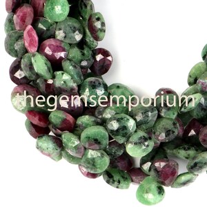 Op de afbeelding: Een streng groene en rode edelsteen kralen. De kralen zijn gefacetteerd en hebben een ruwe, natuurlijke uitstraling. De kralen zijn ovaalvormig en hebben een mix van groene en rode kleuren.