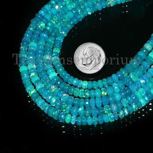 May include: A strand of turquoise blue opal beads with a green iridescent sheen. The beads are faceted and have a slightly irregular shape. The beads are approximately the size of a UK ten pence coin.