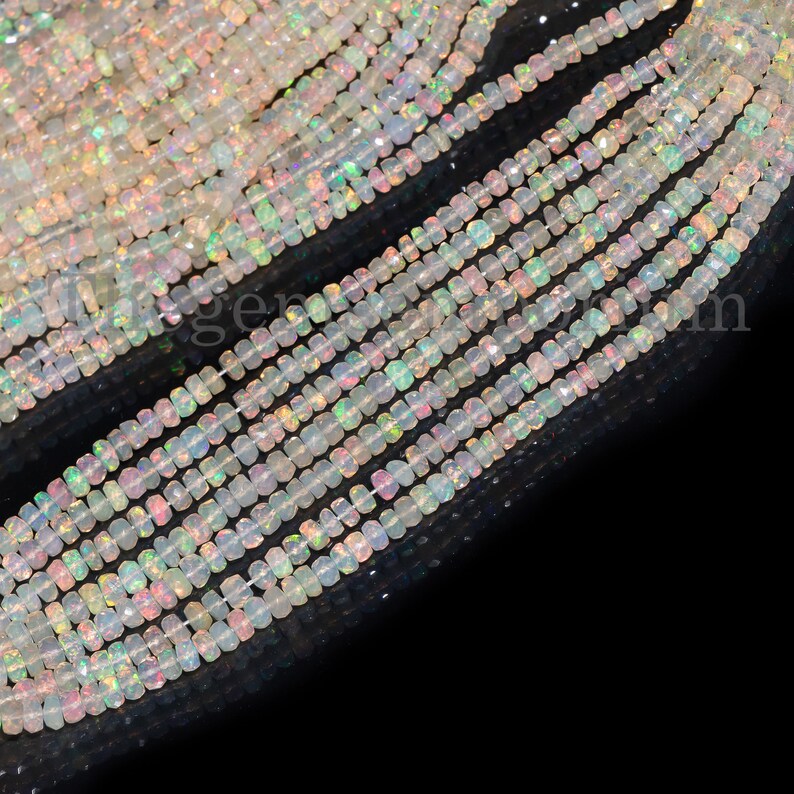 May include: A strand of white opal beads with iridescent rainbow colors. The beads are faceted and have a square shape. The beads are strung on a clear thread and are approximately 4mm in size.