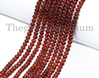 May include: Strands of small, round, reddish-brown beads. The beads are strung together, creating multiple parallel lines. The beads have a polished, glossy appearance. The background is white.