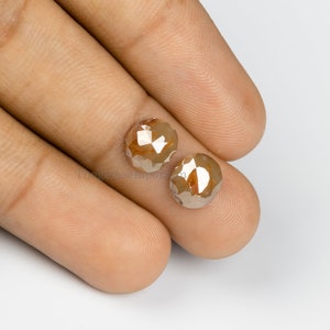 May include: Two round, brown, faceted diamonds. The diamonds are approximately 5mm in diameter and have a rough, natural finish.