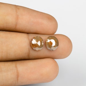 May include: Two oval-shaped, brown, faceted diamonds. The diamonds are set in a bezel setting and have a polished finish.