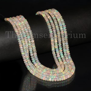 May include: A strand of white opal beads with iridescent rainbow flashes. The beads are faceted and have a slightly rounded shape. The strand is approximately 18 inches long.