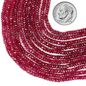 May include: A strand of ruby red faceted beads, approximately 4mm in size, with a US dime for scale.