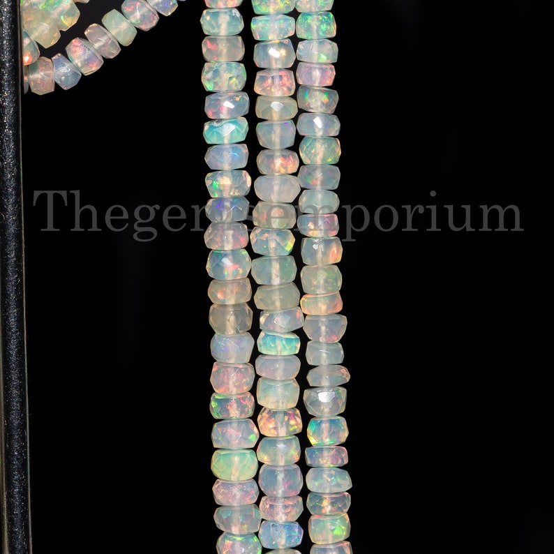 May include: A strand of white opal beads with a faceted, rectangular shape. The beads are strung on a wire and are approximately 6mm in size.