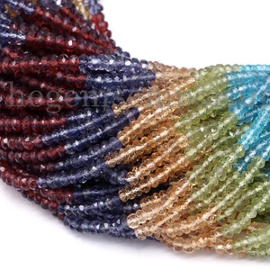 Può includere: Un filo di perline di pietre preziose sfaccettate in vari colori, tra cui rosso, blu, verde e marrone. Le perline sono piccole e di dimensioni uniformi e sono infilate su un filo trasparente.