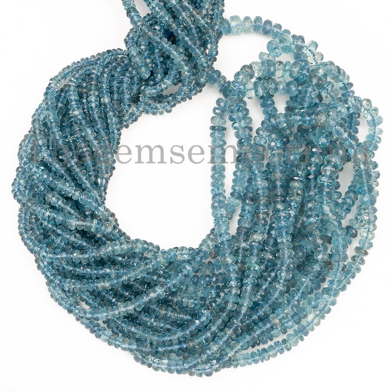 May include: A strand of light blue gemstone beads. The beads are faceted and have a slightly irregular shape. The beads are strung on a clear thread.