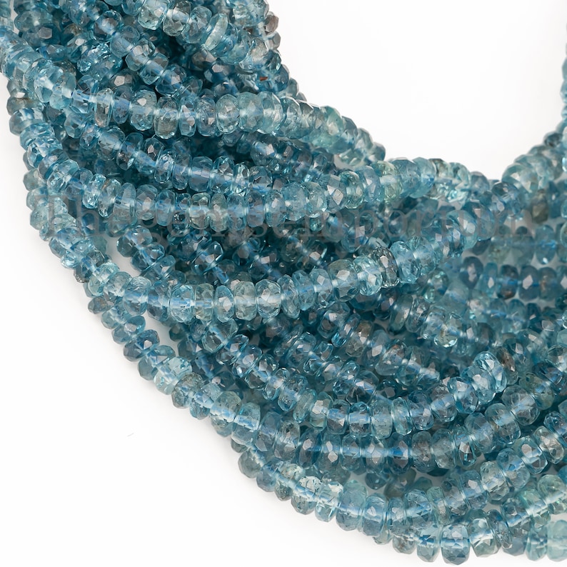 May include: A strand of blue topaz beads, faceted and round, with a smooth, polished finish. The beads are strung together on a clear thread, creating a delicate and elegant necklace.