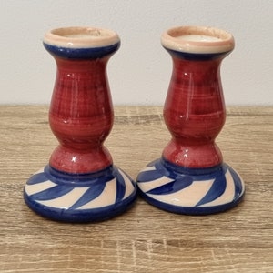 May include: A pair of red and blue ceramic candle holders with a white swirl design.
