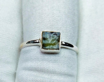 May include: A silver ring with a square-shaped green gemstone.