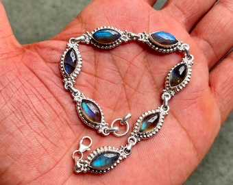 May include: A silver bracelet with oval-shaped labradorite gemstones. The bracelet has a lobster clasp closure.