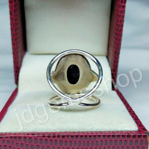 May include: A silver ring with a black stone set in a silver oval. The ring is in a red velvet box.