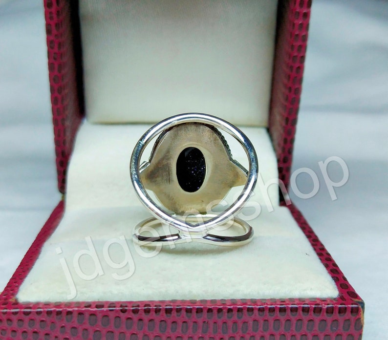 May include: A silver ring with a black stone set in a silver oval. The ring is in a red velvet box.