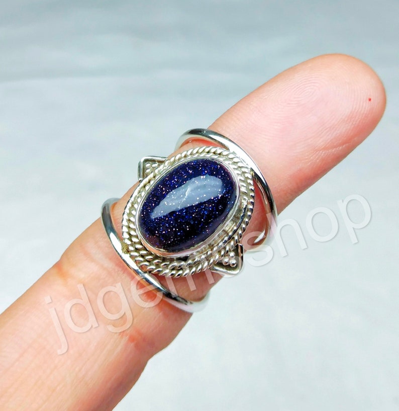 May include: A silver ring with a blue star-shaped gemstone set in a silver bezel. The ring has a twisted band and a decorative design.