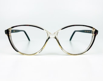 May include: Clear-framed eyeglasses with a cat-eye shape. The frames have black and burgundy accents on the outer edges and temples. The lenses are clear, and the arms are thin and black. The glasses are set against a white background.