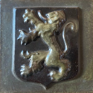 Peut inclure: Un carreau de céramique avec un lion vert et noir en relief dans une forme de bouclier.