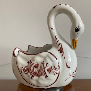 May include: White ceramic swan planter with a brown floral design. The swan has a yellow beak and black eyes.