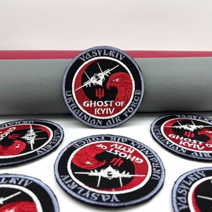 May include: Five round embroidered patches with a black background, red and white accents, and a stylised image of a fighter jet. The patches feature the text "Ghost of Kyiv" and "Ukrainian Air Force".