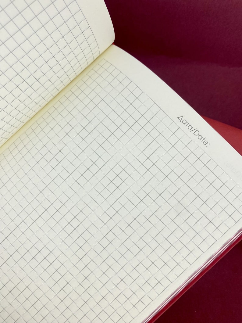 May include: An open notebook with a grid pattern on the pages. The notebook has a red cover and the words "Area/Date:" are printed on the right side of the page.