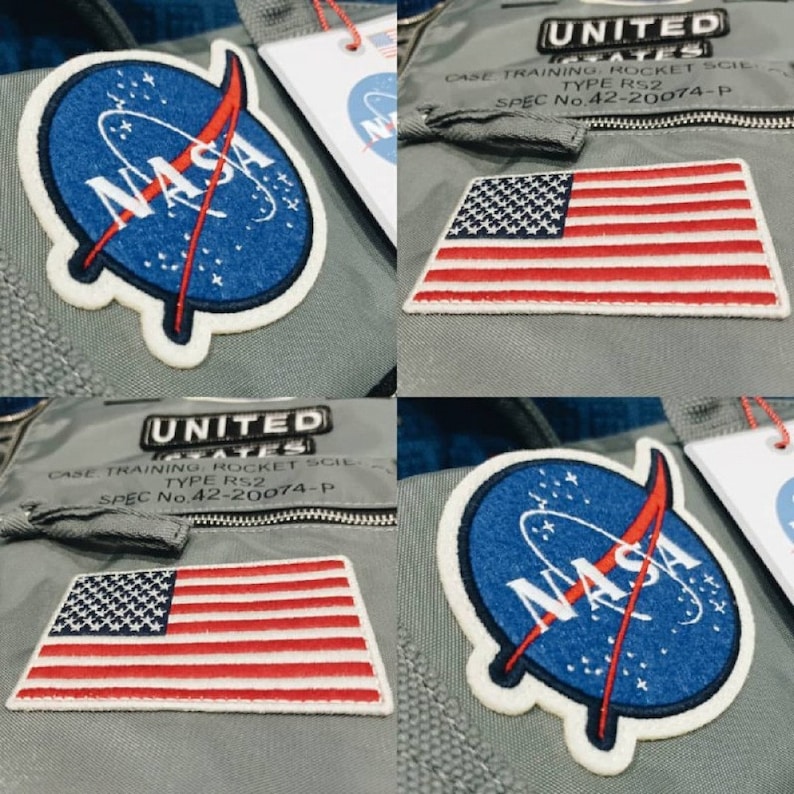 Puede incluir: Dos parches con el logotipo de la NASA y la bandera estadounidense sobre un fondo gris. Los parches est&aacute;n rodeados de costuras blancas. El texto "UNITED STATES CASE TRAINING ROCKET SCIENCE TYPE RS2 SPEC No.42-20074-P" es visible en el fondo.