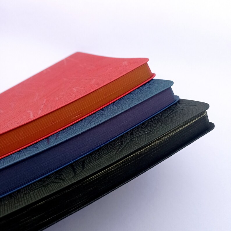 May include: A stack of three notebooks with different colored covers. The top notebook is red, the middle notebook is blue, and the bottom notebook is black.