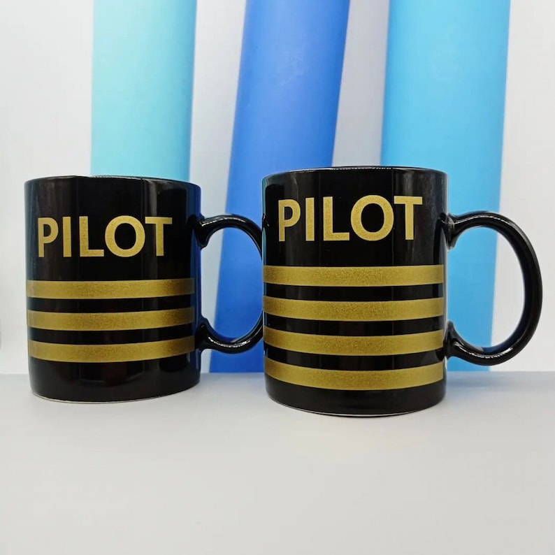 May include: Two black ceramic mugs with gold stripes and the word "PILOT" printed in gold letters.