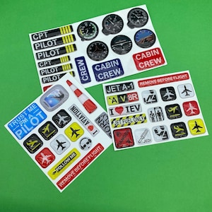 May include: A set of colourful stickers with aeroplane and pilot themes. The stickers feature phrases like "Trust Me - I'm A Pilot", "Cabin Crew", "Jet A-1", and "Remove Before Flight".