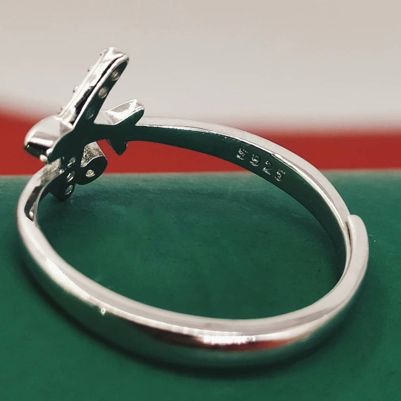 Op de afbeelding: Zilveren vliegtuigring met een heldere steen op de vleugel. De ring is gemarkeerd met "925" aan de binnenkant van de band.