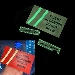 以下が含まれることがあります： 黒い文字で「FLIGHT RECORDER DO NOT OPEN」と書かれた、暗闇で光るステッカーが2つ。1つは白のストライプが入った赤色、もう1つは白のストライプが入った緑色です。