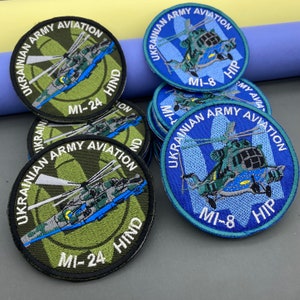 May include: Two round embroidered patches featuring a helicopter with the text "UKRAINIAN ARMY AVIATION" and the helicopter model and name. One patch is green and blue with the text "MI-24 HIND". The other patch is blue with the text "MI-8 HIP".