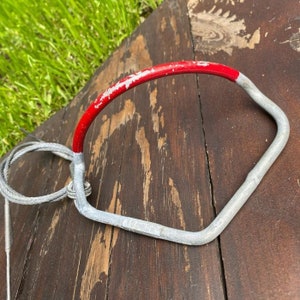 May include: A silver metal handle with a red painted top. The handle is attached to a silver cable.