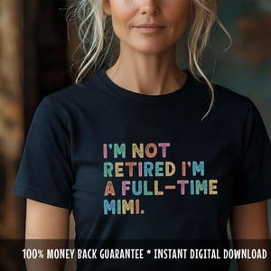 May include: A black crew neck t-shirt featuring the phrase "I'M NOT RETIRED I'M A FULL-TIME MIMI" in colourful block letters. The text is in a rainbow of colours.
