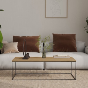 Peut inclure: Un canapé blanc avec des coussins en velours marron et une table basse en bois avec un cadre en métal noir. Le canapé est dans un salon avec un tapis beige et une plante en pot.