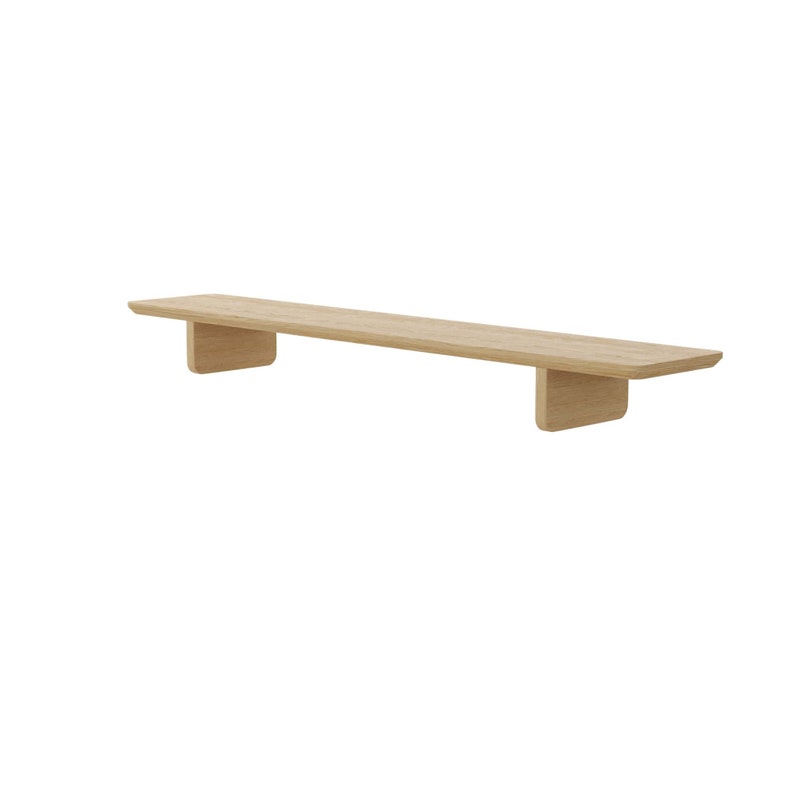 Puede incluir: Una estanter&iacute;a flotante de madera clara con bordes redondeados y un dise&ntilde;o sencillo. La estanter&iacute;a est&aacute; montada en la pared con dos soportes.