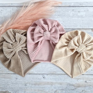 May include: Three fabric headbands with a bow detail. The headbands are in shades of pink, beige, and brown.