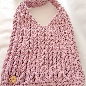 Puede incluir: Un bolso de hombro de crochet rosa con una correa trenzada y una etiqueta de madera que dice "Handmade with Love".