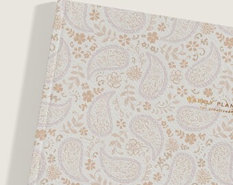 Könnte beinhalten: Ein weißer Planer mit einem Paisley-Muster in hellbraun und einem goldenen Titel, der "Weekly Planner for Creatives" lautet.