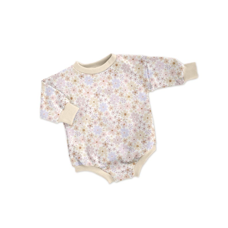 May include: A baby's floral print romper in soft pastel colors. The long-sleeved one-piece features a cream-colored neckline and cuffs. The romper is covered in a pattern of small flowers in shades of pink, lavender, and beige.