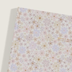 May include: A white planner with a floral pattern in shades of pink, purple, and beige. The text "WEEKLY PLAN for creatives" is printed in gold on the cover.
