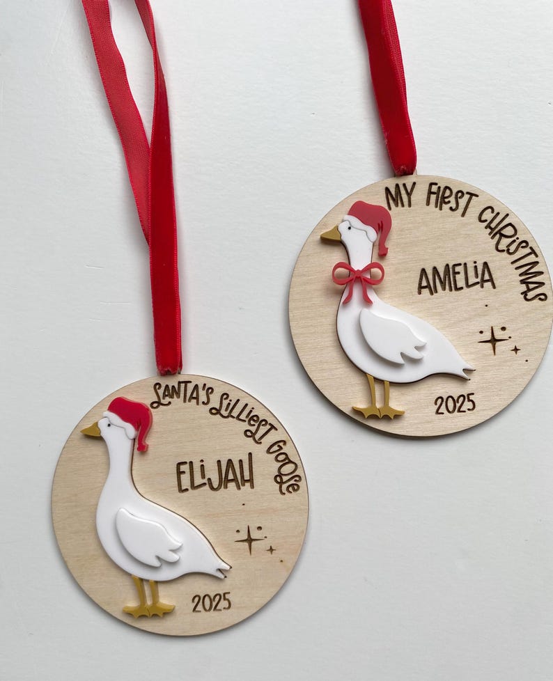 May include: Two wooden Christmas ornaments with red ribbons. Each ornament features a white goose wearing a Santa hat and the text "My First Christmas" or "Santa's Silliest Goose" with a name and the year 2025.