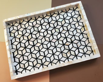 May include: A white rectangular tray with a black geometric pattern. The tray is made of mother of pearl and has a glossy finish.