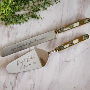 May include: A silver cake knife and server set with gold handles and mother-of-pearl inlays. The knife has the inscription "50 years looking outward together in the same direction". The server has the inscription "Doug & Rachel 28 October 1972 - 2022".