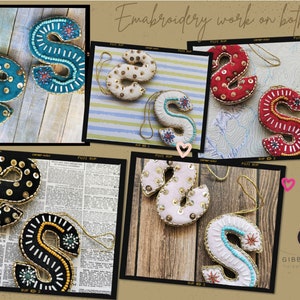 May include: Five embroidered felt letter S ornaments in different colors and patterns. The ornaments are decorated with sequins, beads, and embroidery. The text "Embroidery work on both sides" is visible in the image.