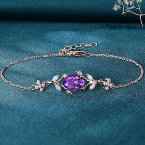 May include: A delicate rose gold bracelet with a purple amethyst gemstone surrounded by white opal accents. The bracelet features a floral design with leaves and small white stones.