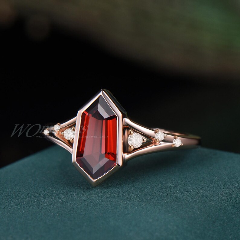 K&ouml;nnte beinhalten: Ein Ring aus Ros&eacute;gold mit einem gro&szlig;en, roten, achteckigen Edelstein, der von kleineren, klaren Edelsteinen umgeben ist.